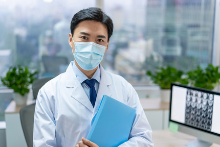 年轻医生戴着口罩在办公室工作照片