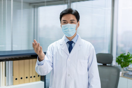 年轻医生戴着口罩在办公室工作照片