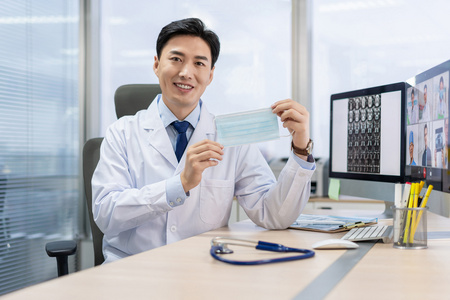 年轻医生戴着口罩在办公室工作照片