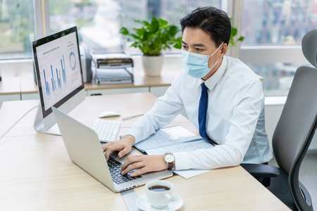 年轻商务男士戴着口罩办公照片