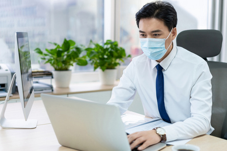 年轻商务男士戴着口罩办公照片