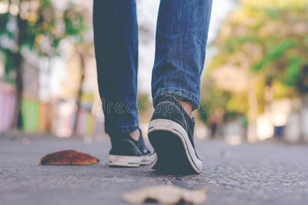 男人使人疲乏的橡皮底帆布鞋和牛仔裤步行一起城市大街.照片