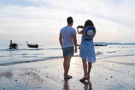 对海滩夏假期,男人女人拿照片日落年幼的照片