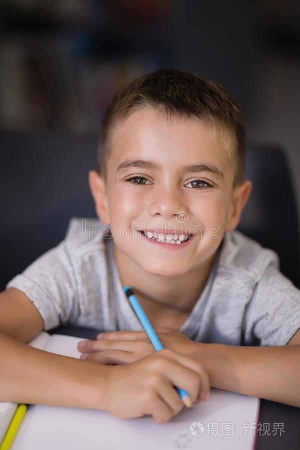 肖像关于微笑的男生做他的家庭作业采用图书馆