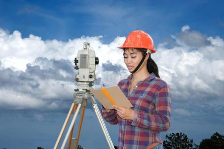 女性的测量员或工程师制造测量在旁边经纬仪向指已提到的人照片
