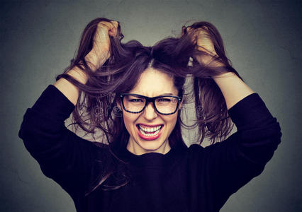 拉绳子强调生气的女人拉头发出局尖叫的向灰色墙用绳子拖的平底渡船