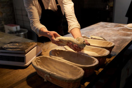 手艺厨师面包师和生面团上升的采用篮在面包房照片