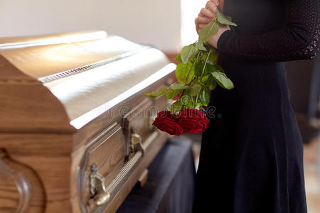 女人和红色的玫瑰和棺材在葬礼照片