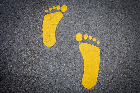 黄色的脚印手势向一沥青路照片