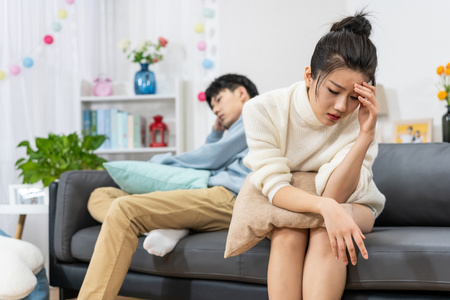 年轻情侣在客厅沙发上争吵照片