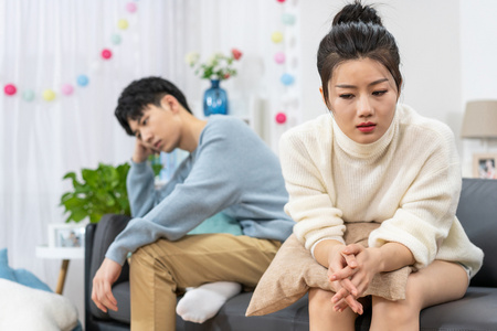 年轻情侣在客厅沙发上争吵照片