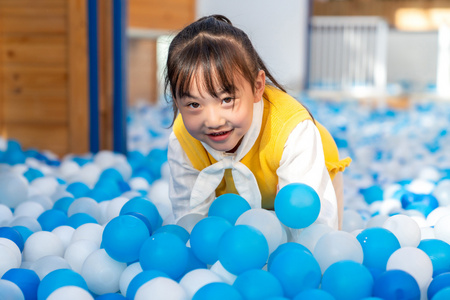 婴儿宝宝坐在尿布与绿色蓝色砖玩具和红色球玩裸可爱的宝宝玩玩具球