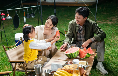 一家人夜晚傍晚一家人在露营地吃西瓜照片