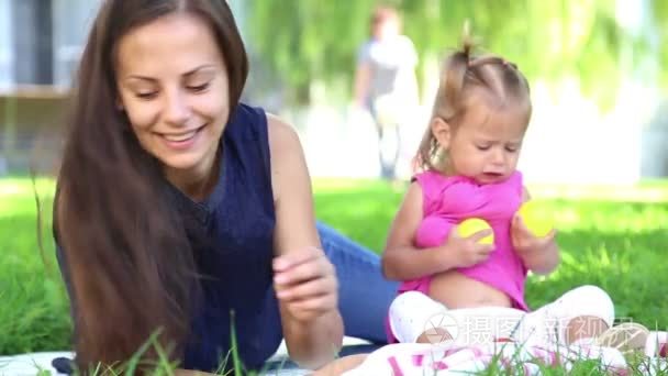 年轻的母亲抱着婴儿玩带孩子在公园里有一个小姑娘在自然公园的 vacation.mom grass.family 市 park.m