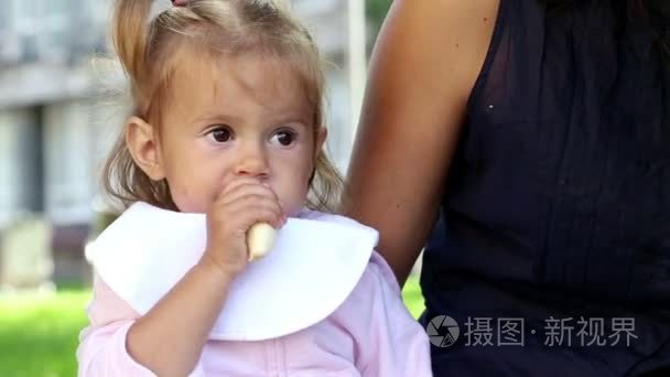 年轻漂亮的妈妈喂孩子在 park.young 母亲与婴儿午餐上 grass.mom 饲料在公园里拍孩子在我母亲旁边的公园里的小女