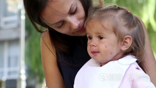 年轻漂亮的妈妈喂孩子在 park.young 母亲与婴儿午餐上 grass.mom 饲料在公园里拍孩子在我母亲旁边的公园里的小女