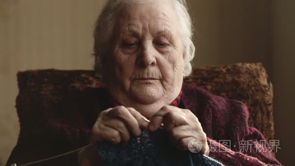 老妇人坐在家里和针织服装视频