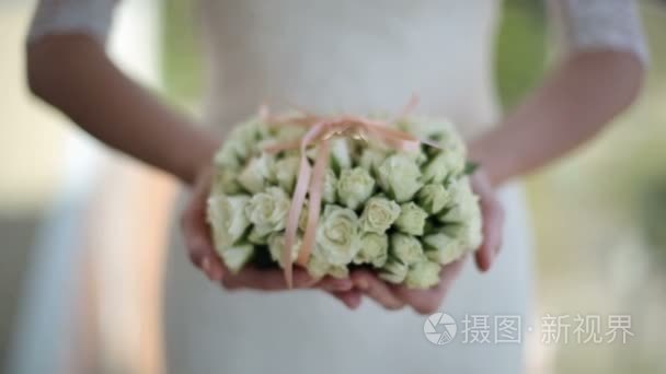 新娘抱着一束鲜花和结婚戒指