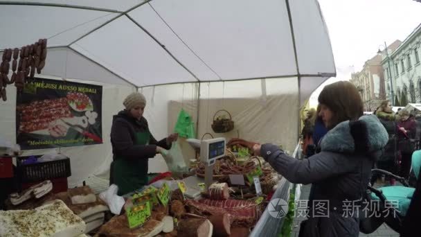 女人付钱，购买天然烟熏的肉类食品市场