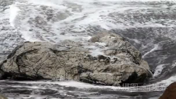 波与海滩上的岩石的近景视频