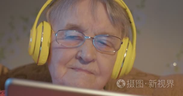 Senior woman in headphones using tablet computer