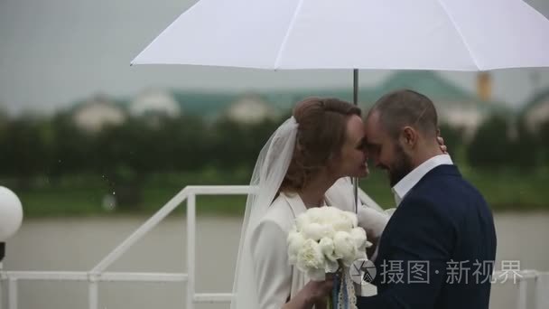 新婚夫妇在露台的伞走在雨天视频