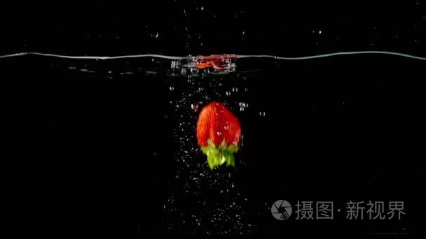 在黑色背景上掉到水里草莓视频