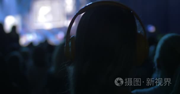 女人在音乐会上的人群中戴上耳机