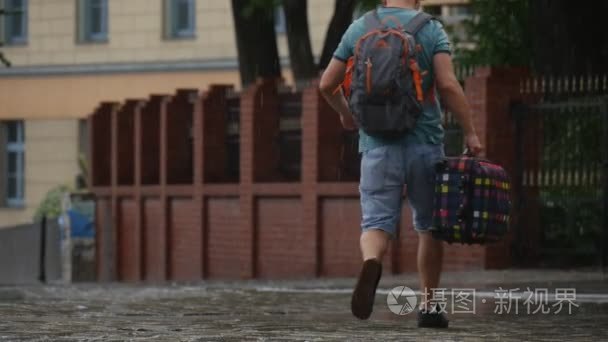 背上背包和格子行李箱走在雨中无伞湿的人行道停放车在波兰奥波莱慢动作夏季雨天关闭了的男人