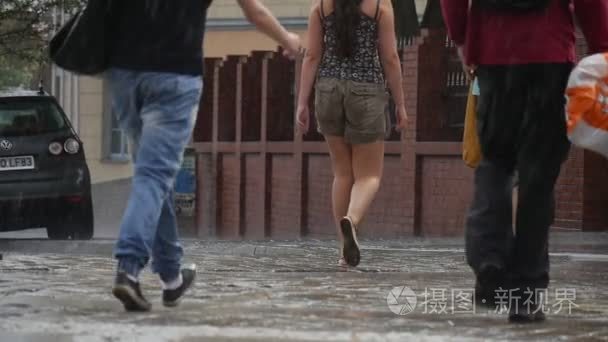 三个妇女和男人走在雨中湿在人行道上他们砖围墙夏季雨天在奥波莱波兰慢动作关闭视图右侧