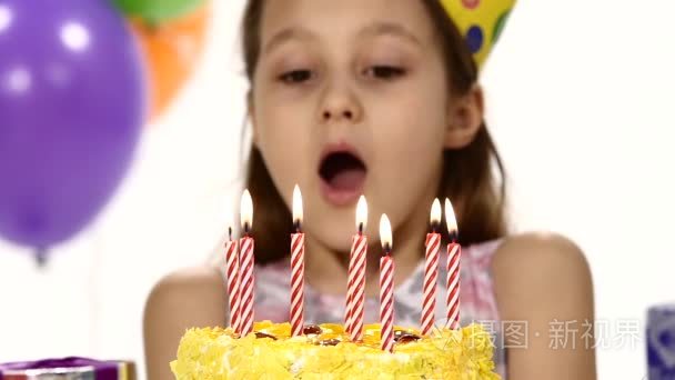 Birthday girl blows out  candles on a birthday cake. In the back