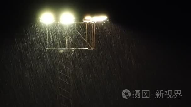 Stadium floodlights at night during a heavy rain shower.