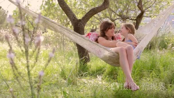 mother and daughter sitting together in a hammock