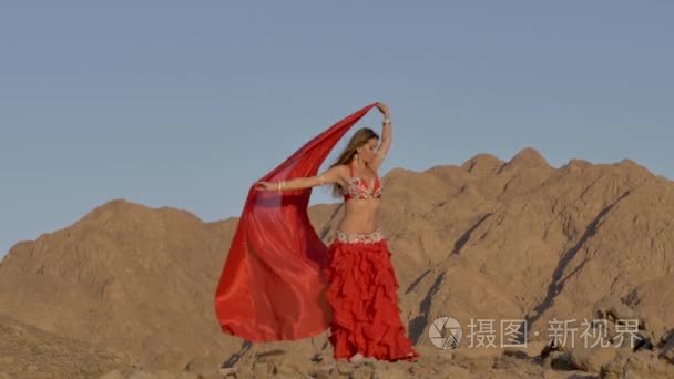 在沙漠里跳民族舞蹈的美丽女孩