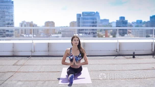 女人做瑜伽和普拉提练习城市摩天大楼的屋顶上视频