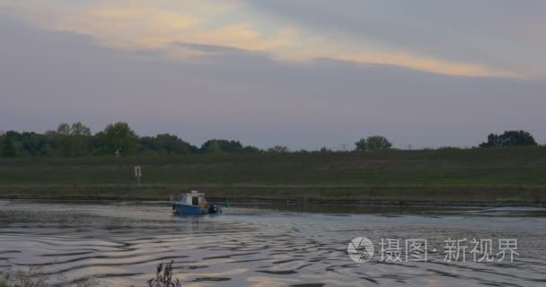 机动船是由浮河池塘湖船是移动离开地平线绿色草地场灰色天空荡漾水电机船跟踪绿色树