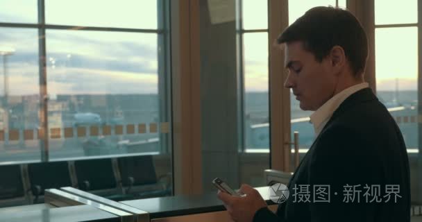 年轻人在机场中键入短信视频
