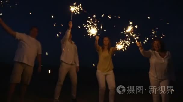 Family with sparklers on the beach at night