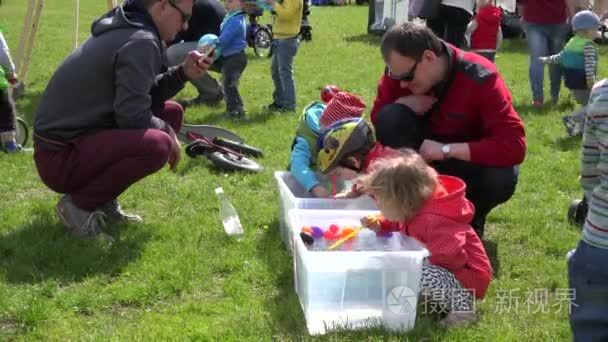 Boys and girls play duck race in small water pool with straw. 4K视频