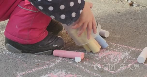 小女孩举手附近需要关闭从桶里的粉笔和他们再把女儿放在夹克的波尔卡圆点的靴子图片上沥青冬季