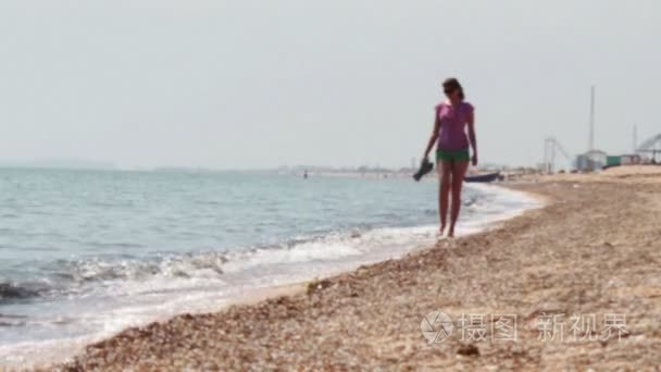 Beautiful girl goes on the beach the sea coast.