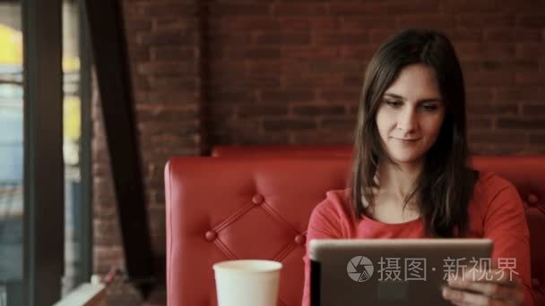 使用平板电脑触摸屏，在咖啡厅喝下午茶的女人
