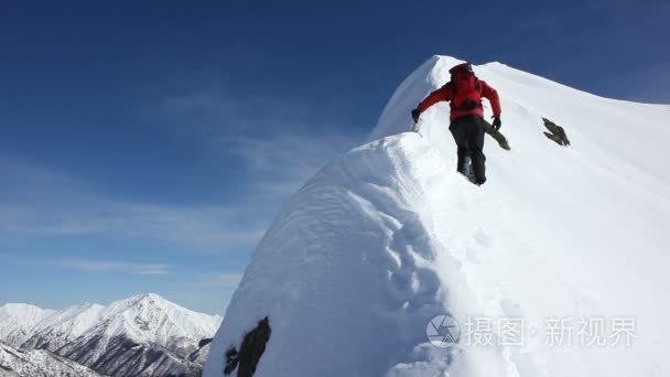 登山者攀登白雪皑皑的山脊视频