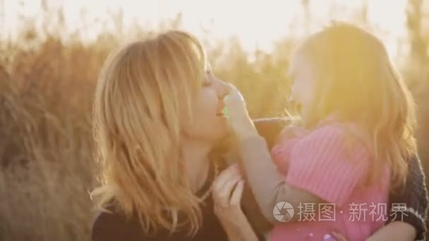 小女孩和母亲接吻玩在夕阳的光视频
