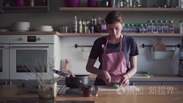 年轻的女孩在厨房里做饭的围裙视频