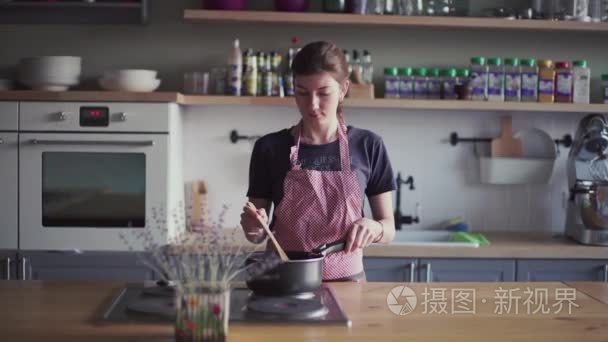 年轻的女孩在厨房里做饭的围裙视频
