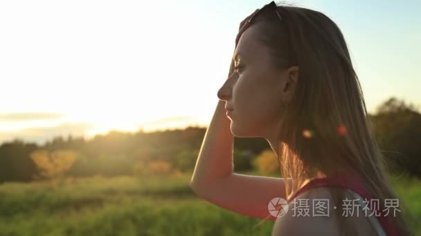 年轻的女人坐在公园里放太阳眼镜和读一本书