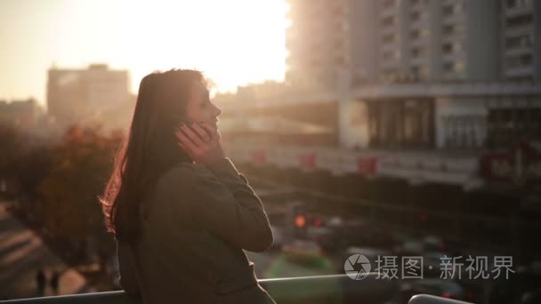 漂亮的女人谈在城市桥梁上电话视频