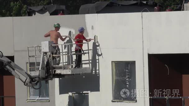 worker on scaffolding paint the wall white with roller . 4K