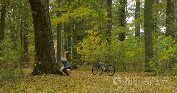 Ushanka 戴着帽子的男人拿笔记本电脑从背包坐下的树自由职业者程序员文案设计师会计工作在秋天